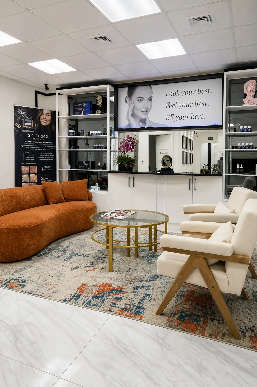 The patient lounge, with an orange sofa, cream armchairs and the skincare display wall